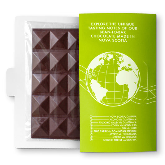 A packaged chocolate bar with a green label that includes an illustration of a globe and text indicating the origin of the cacao beans. The chocolate bar is labeled as 'Single Varietal PISA, Haiti 70 g'.